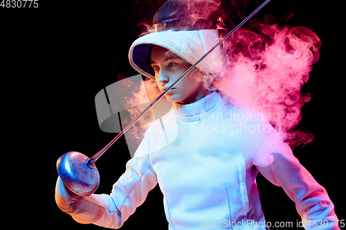 Image of Teen girl in fencing costume with sword in hand isolated on black background