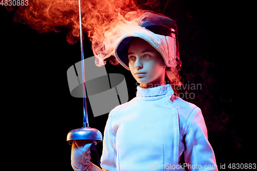 Image of Teen girl in fencing costume with sword in hand isolated on black background