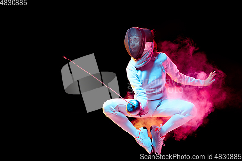 Image of Teen girl in fencing costume with sword in hand isolated on black background