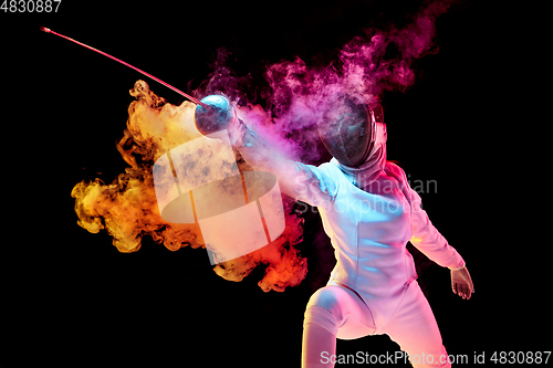 Image of Teen girl in fencing costume with sword in hand isolated on black background