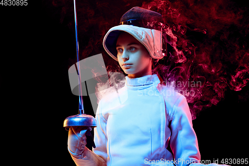 Image of Teen girl in fencing costume with sword in hand isolated on black background