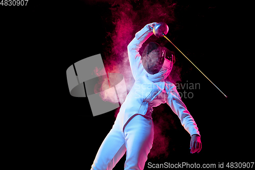 Image of Teen girl in fencing costume with sword in hand isolated on black background