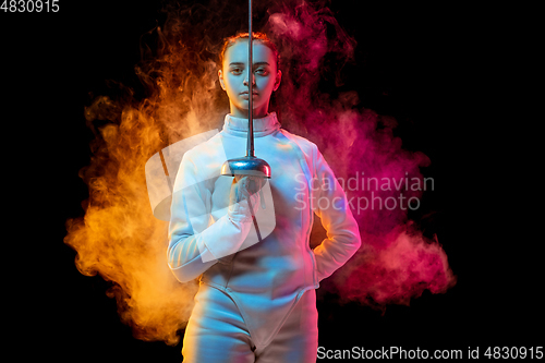 Image of Teen girl in fencing costume with sword in hand isolated on black background