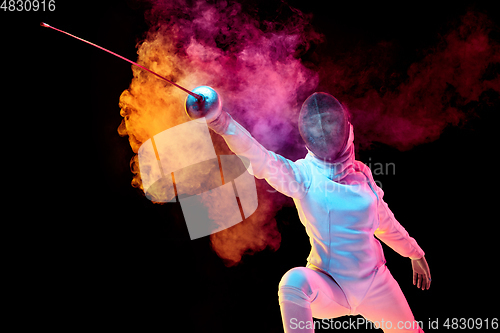 Image of Teen girl in fencing costume with sword in hand isolated on black background