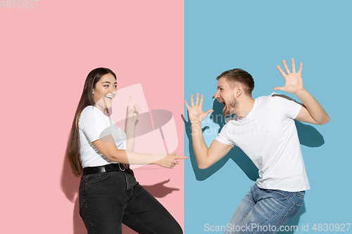 Image of Young emotional man and woman on pink and blue background