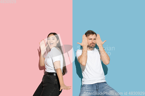Image of Young emotional man and woman on pink and blue background
