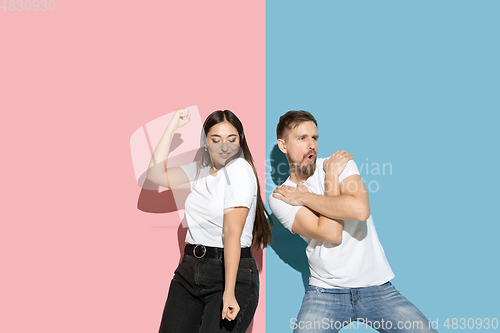 Image of Young emotional man and woman on pink and blue background