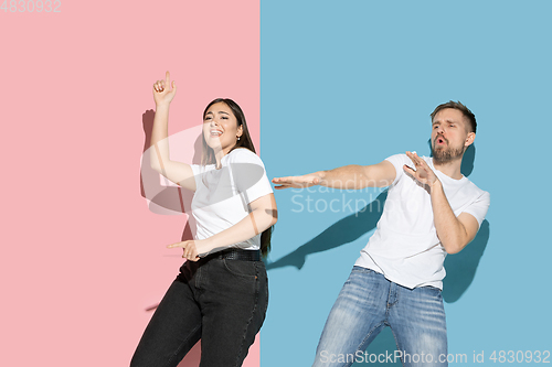 Image of Young emotional man and woman on pink and blue background