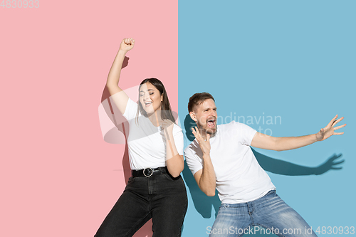 Image of Young emotional man and woman on pink and blue background