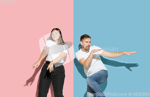 Image of Young emotional man and woman on pink and blue background