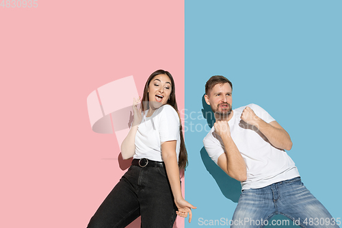 Image of Young emotional man and woman on pink and blue background