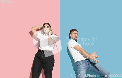 Image of Young emotional man and woman on pink and blue background