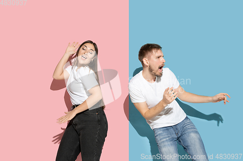 Image of Young emotional man and woman on pink and blue background