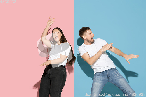 Image of Young emotional man and woman on pink and blue background
