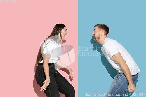 Image of Young emotional man and woman on pink and blue background