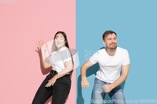 Image of Young emotional man and woman on pink and blue background