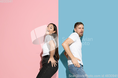 Image of Young emotional man and woman on pink and blue background
