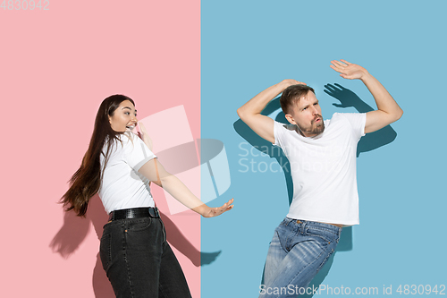 Image of Young emotional man and woman on pink and blue background