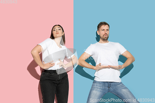 Image of Young emotional man and woman on pink and blue background