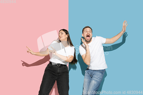 Image of Young emotional man and woman on pink and blue background