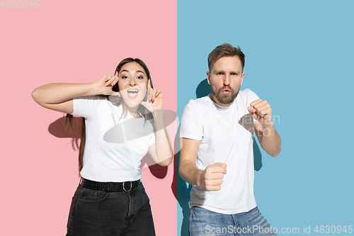 Image of Young emotional man and woman on pink and blue background