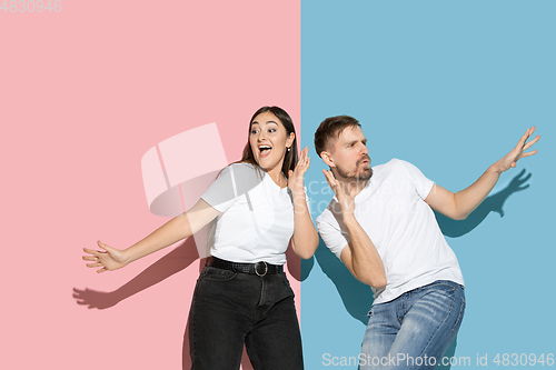 Image of Young emotional man and woman on pink and blue background