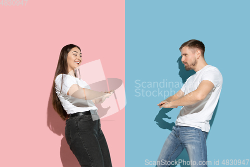 Image of Young emotional man and woman on pink and blue background