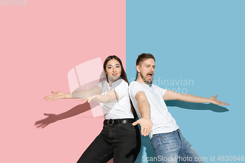 Image of Young emotional man and woman on pink and blue background