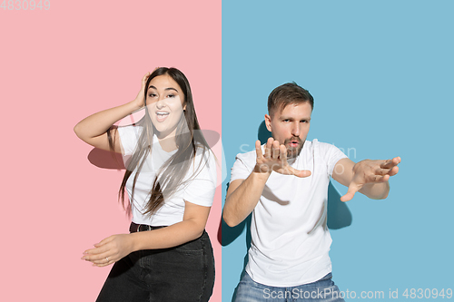 Image of Young emotional man and woman on pink and blue background