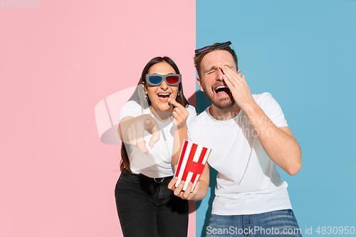 Image of Young emotional man and woman on pink and blue background