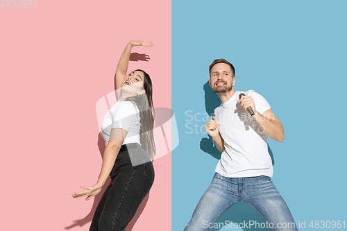 Image of Young emotional man and woman on pink and blue background