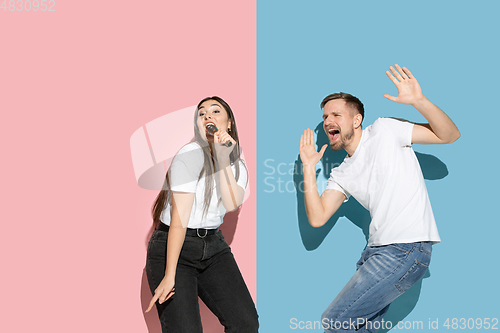 Image of Young emotional man and woman on pink and blue background