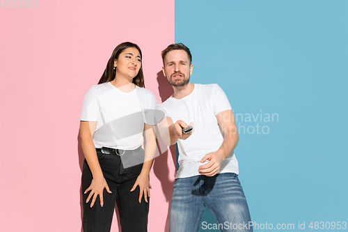 Image of Young emotional man and woman on pink and blue background