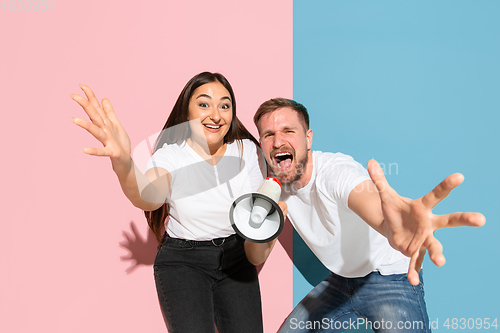 Image of Young emotional man and woman on pink and blue background
