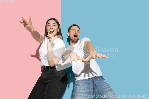 Image of Young emotional man and woman on pink and blue background