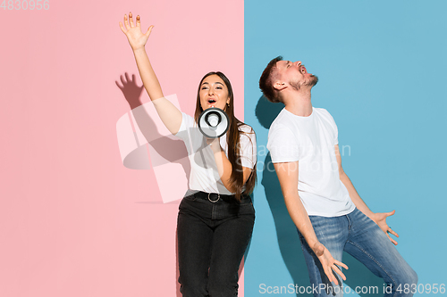 Image of Young emotional man and woman on pink and blue background