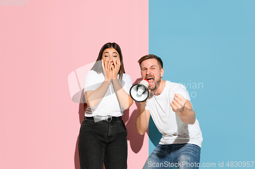 Image of Young emotional man and woman on pink and blue background