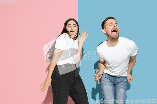 Image of Young emotional man and woman on pink and blue background