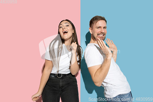 Image of Young emotional man and woman on pink and blue background