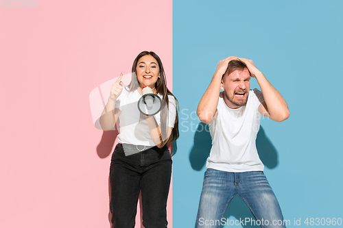 Image of Young emotional man and woman on pink and blue background