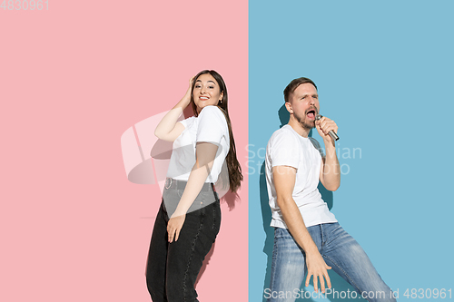 Image of Young emotional man and woman on pink and blue background