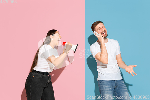 Image of Young emotional man and woman on pink and blue background