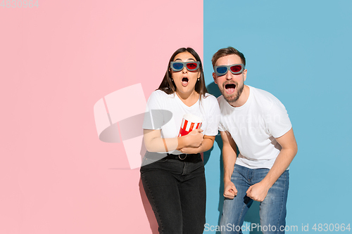 Image of Young emotional man and woman on pink and blue background