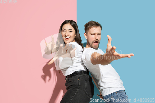 Image of Young emotional man and woman on pink and blue background