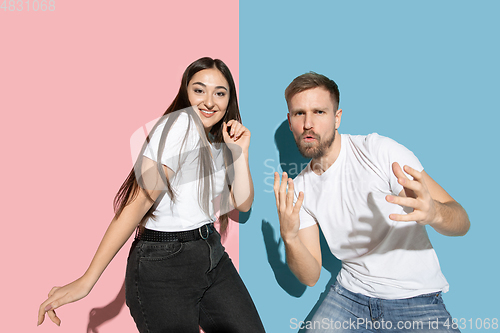 Image of Young emotional man and woman on pink and blue background