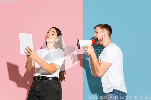 Image of Young emotional man and woman on pink and blue background