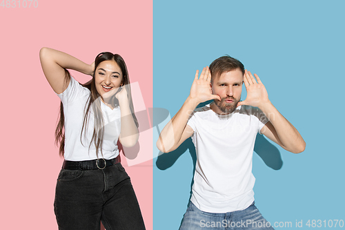 Image of Young emotional man and woman on pink and blue background