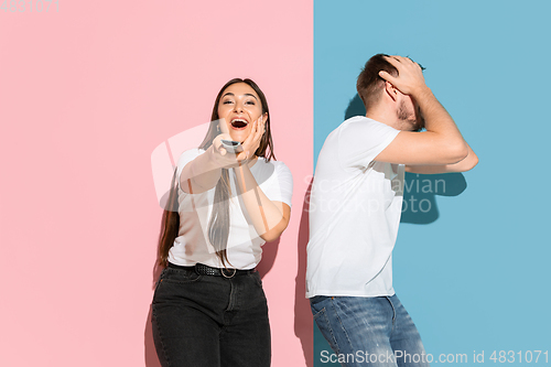 Image of Young emotional man and woman on pink and blue background