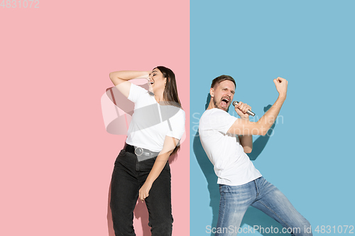 Image of Young emotional man and woman on pink and blue background