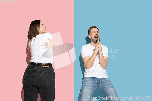 Image of Young emotional man and woman on pink and blue background